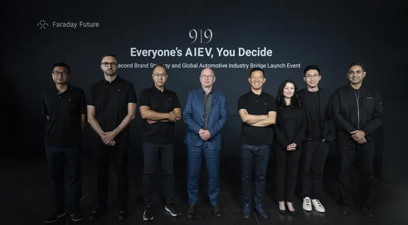 A group of people standing in front of a sign

Description automatically generated